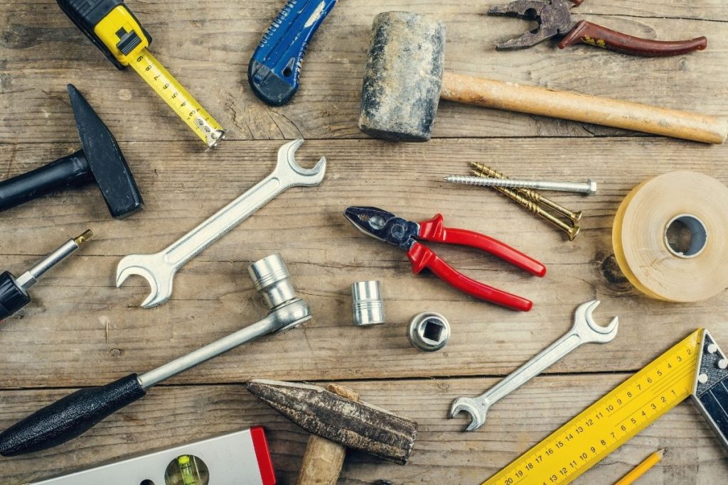 Various hand tools scattered on a wooden table, illustrating a range of tools used for different tasks.